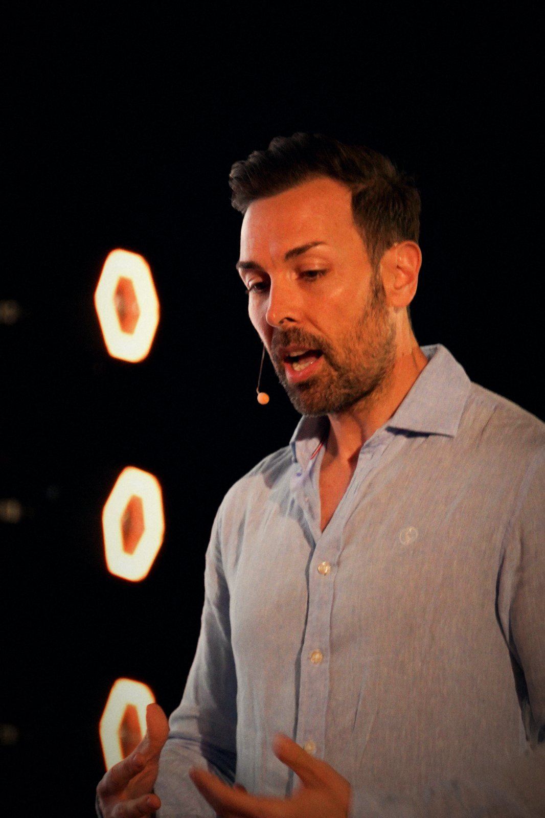 Jose M Bermejo speaking on stage, ring lights behind him